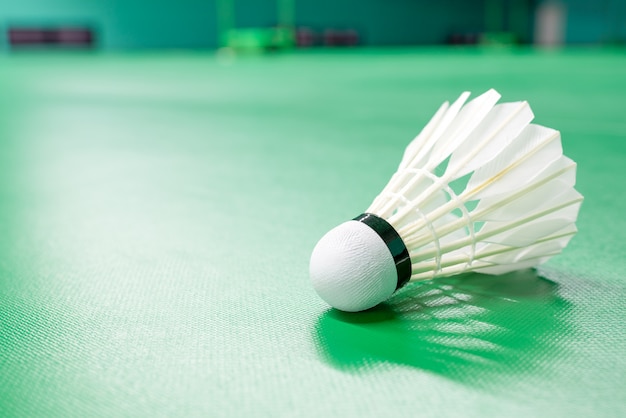 White badminton shuttle cock and neon light shading on a green floor