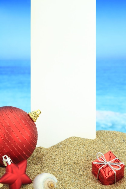 Photo white banner and christmas ornaments on the beach