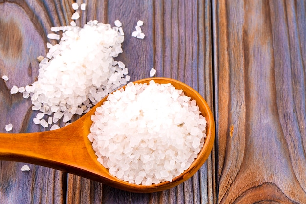 white bath salt in a wooden spoon on wooden table