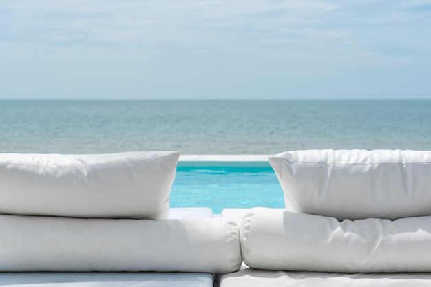 White beach bed at outdoor swimming pool seaside turquoise sea 