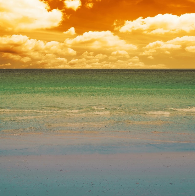 Photo white beach and blue water on a cloudy day at sunset