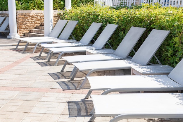 White beach umbrellas and lounge chairs at the swimming pool in hotel and resort