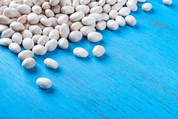 White beans on a blue wooden background Background with lots of beans and space for text