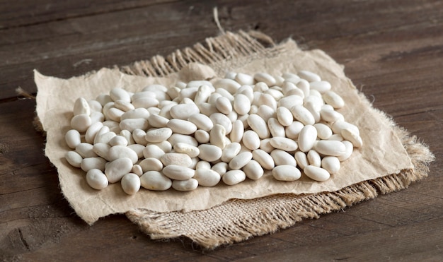 Photo white beans on brown wooden table close up