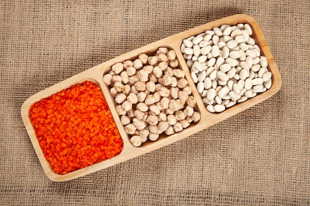 White beans dried chickpeas and red lentils on a wooden plate