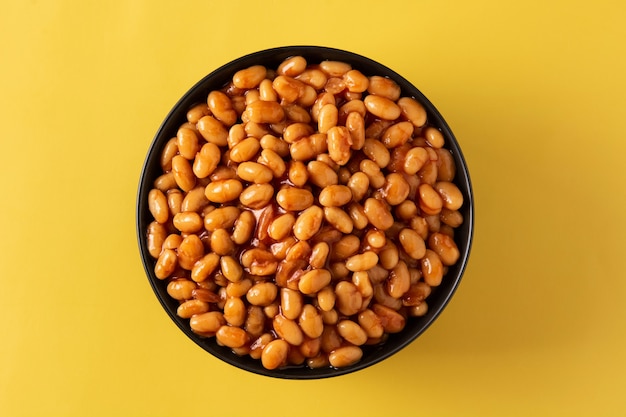 White beans in tomato sauce in bowl on yellow background