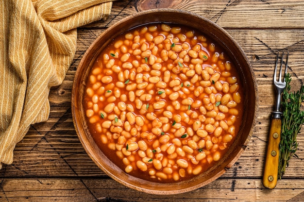 Foto fagioli bianchi in salsa di pomodoro in un piatto di legno