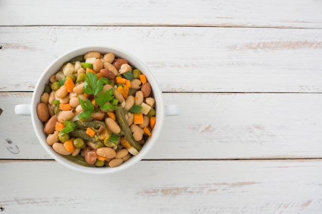 White beans with vegetables on white wooden table top view