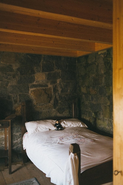 Photo white bed beside a stone wall photo