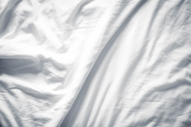 추상 럭셔리 패브릭의 흰색 침대 린넨 그라데이션 질감 흐릿한 곡선 스타일주름이 있는 침대 린넨과 짙은 회색 그림자 배경