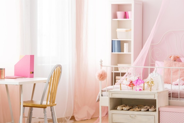 A white bed with a pink bed and a white shelf with a pink curtain