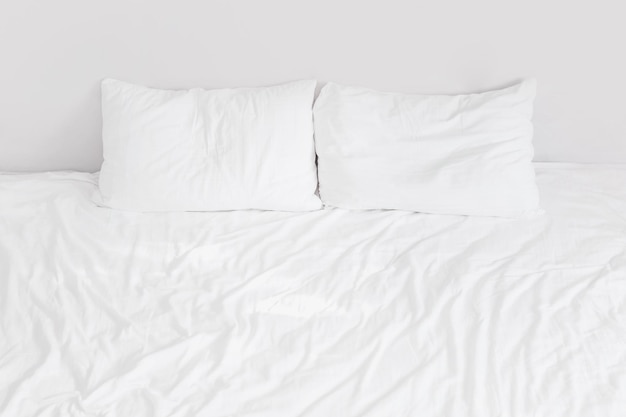 사진 두 개의 베개가 있는 흰색 린넨이 있는 흰색 침대를 닫습니다.
