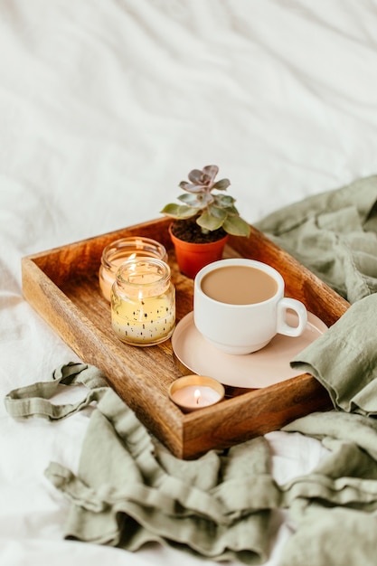 드레싱 가운이 있는 흰색 침구. 커피와 촛불의 트레이입니다. 침대에서 아침 식사.