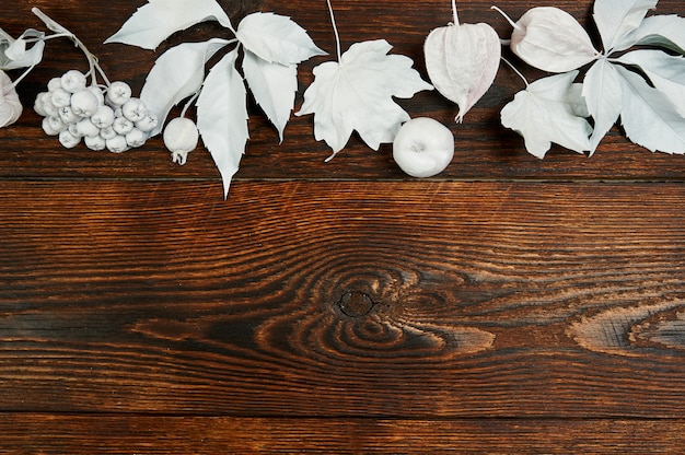 White berries and leaves on a wooden autumn background.