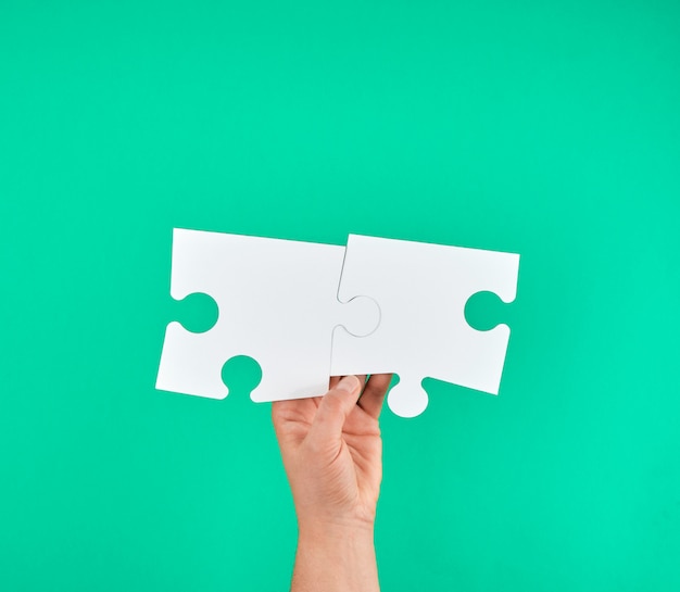 White big puzzle in female hand on green