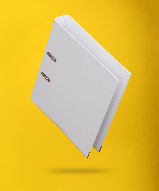white binder with rings levitating on a yellow background with shadow