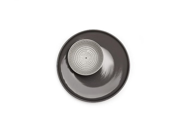A white and black ceramic bowl on a gray plate on a white background with copy space in a top view