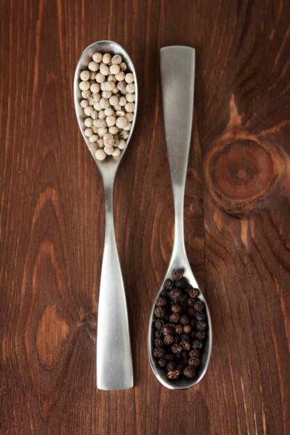 Photo white and black pepper in spoons