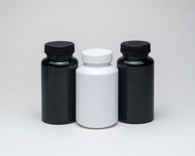 分離された白い背景の上の白と黒のプラスチック製の丸薬瓶