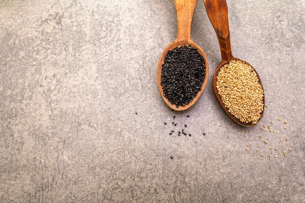 Photo white and black sesame seeds in wooden spoons