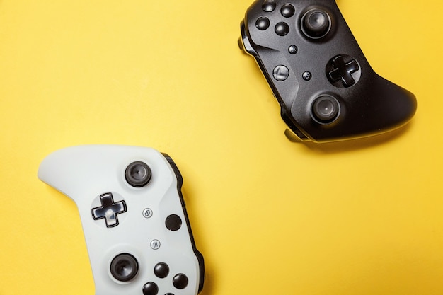 White and black two joystick gamepad, game console on yellow