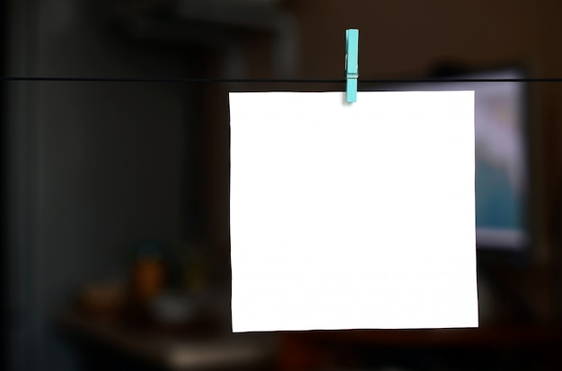 Фото Белая пустая карточка на веревке, темный фон офиса