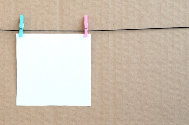 White blank card on rope on a brown cardboard background. 