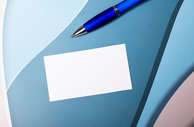 Una carta bianca vuota con un posto per inserire il testo e una penna blu su uno sfondo blu, azzurro e rosa. modello