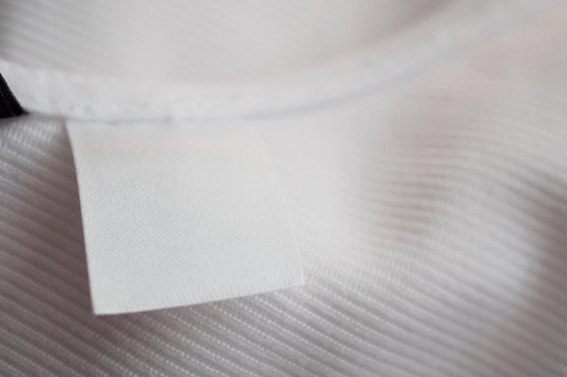 Foto etichetta di abbigliamento bianca bianca su sfondo camicia di cotone