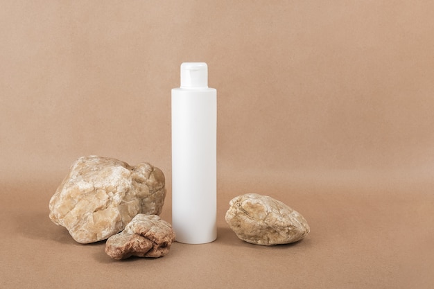 White blank cosmetic bottle with cream, moisturizing lotion or shampoo background on beige craft paper background. Natural Organic Spa Cosmetic concept Front view.