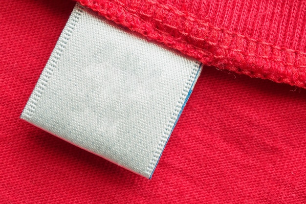 Etichetta di vestiti per la cura della lavanderia in bianco bianco su sfondo rosso della camicia di cotone