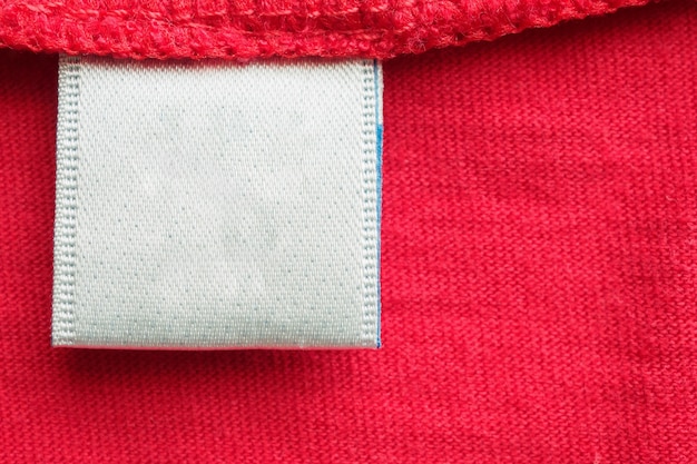 赤い綿のシャツに白い空白のランドリーケア服のラベル