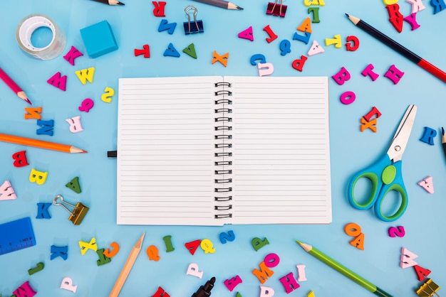 Foto taccuino bianco bianco e materiale scolastico vario su sfondo blu. concetto di scuola. di nuovo a scuola.