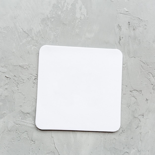 オフィスや自宅の灰色のテーブルの上の白い空白の紙のメモ帳