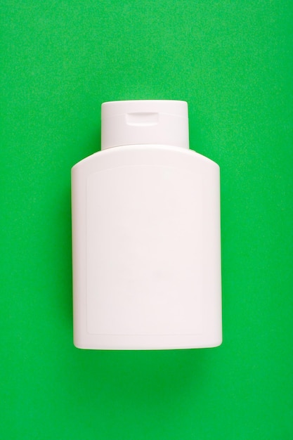 White blank plastic shampoo bottle on green background