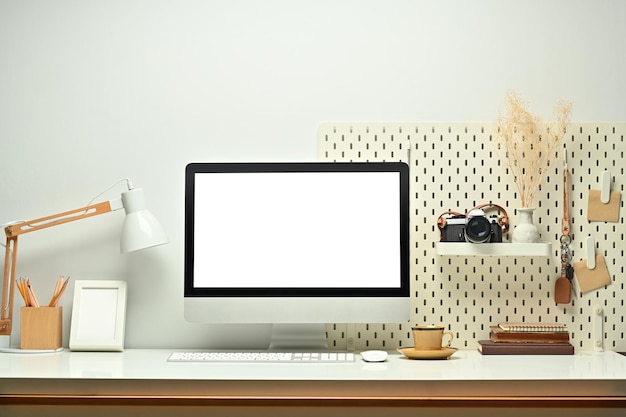 White blank screen computer monitor picture frame camera and books on working table Modern workplace