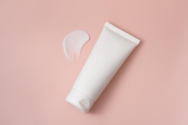 Photo white blank tube of moisturizer or skin lotion with smear on pink isolated background the concept of cosmetics presentation or advertising of a new product