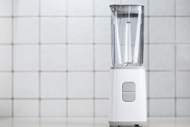 Photo white blender on the table with light kitchen tiles