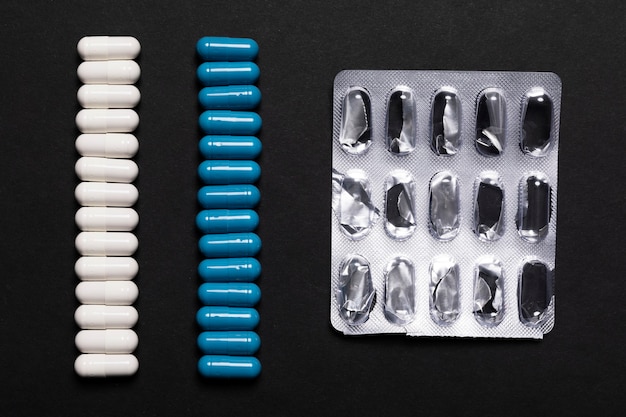 White and blue capsule pills on a black background