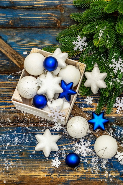 White and blue Christmas balls and stars, fir tree branches and snowflakes. top view