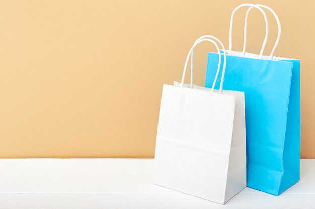 White blue craft paper bags. Shopping Mockup bags paper packages on white table beige copy space.