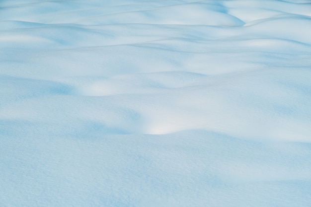 自然な雪の表面の白と青の雪のテクスチャ