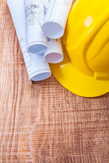 White blueprints and yellow helmet on wooden board