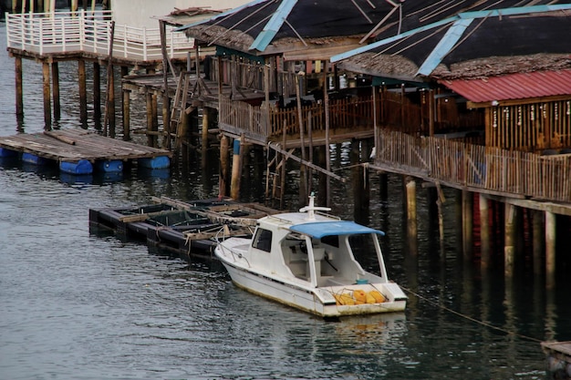 A white boat docking near floating village