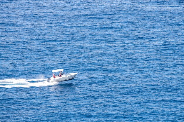 White boat rushing along the blue waves in italy