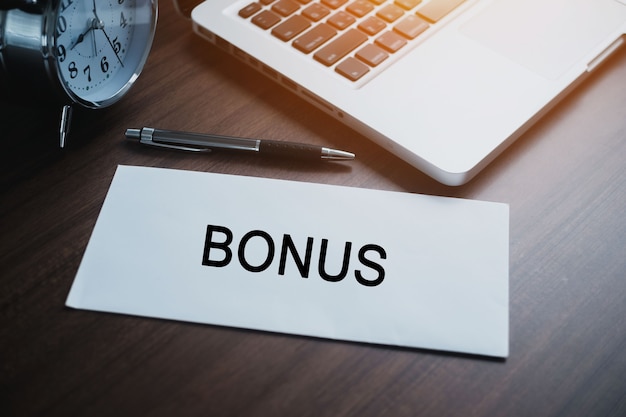 Photo white bonus envelope with laptop computer on a wooden table. the concept of income, bonuses or bribes. corruption, salary, bonus.