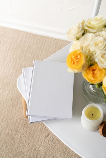 White book blank cover mockup on stylish chair with roses bouquet high angle view