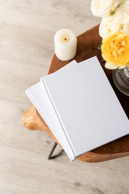 White book blank cover mockup on stylish wooden coffee table with roses bouquet high angle view