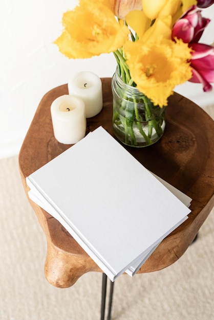 Mockup di copertina in bianco del libro bianco su un elegante tavolino da caffè in legno con vista dall'alto del bouquet di tulipani