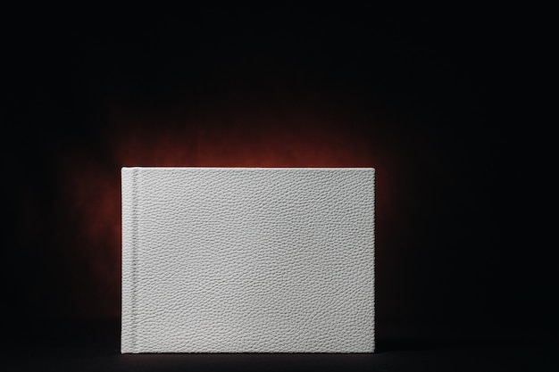 White book in genuine white leather on a dark embossed background . White paper on a dark background.